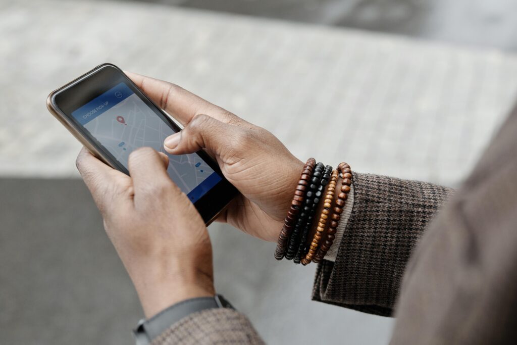 Close-up of hands with bracelets navigating on smartphone using GPS app outdoors.